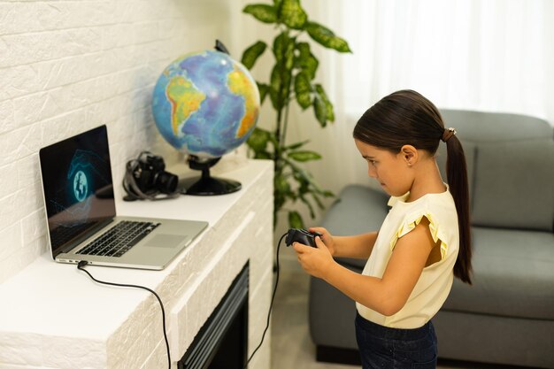 niña jugando con una computadora portátil y un controlador de joystick