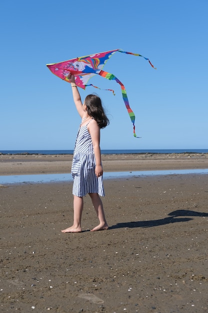 Niña jugando en la costa del mar blanco con una cometa