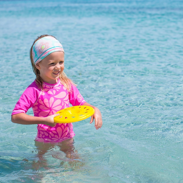 Niña jugando frisbee durante vacaciones tropicales en el mar