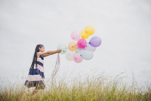 Niña jugando con globos en el campo de prados.