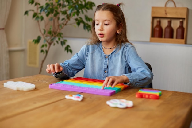 Niña jugando con un gran popit de silicona, un simple hoyuelo, un juguete con forma de burbuja