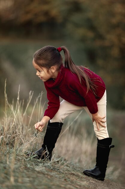 Niña jugando con hojas caídas de otoño