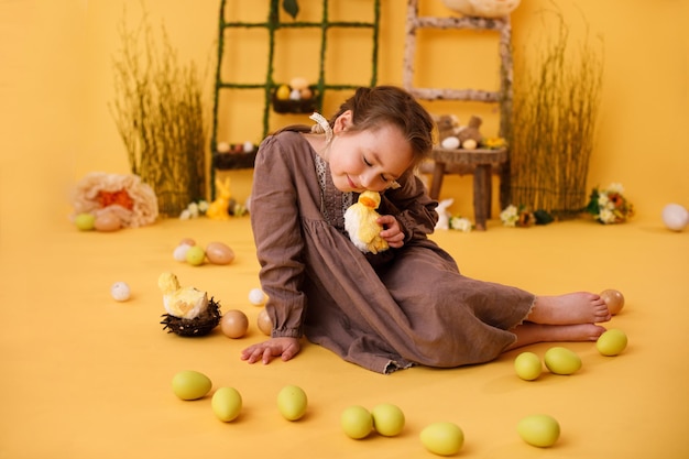 Niña jugando con huevos de pascua y decoración tradicional de pascua de pollo en estilo rural
