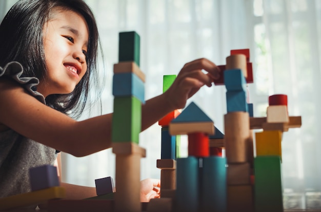 Niña jugando juego constructor torre de bloques de madera multicolores. Concepto de aprendizaje y desarrollo.