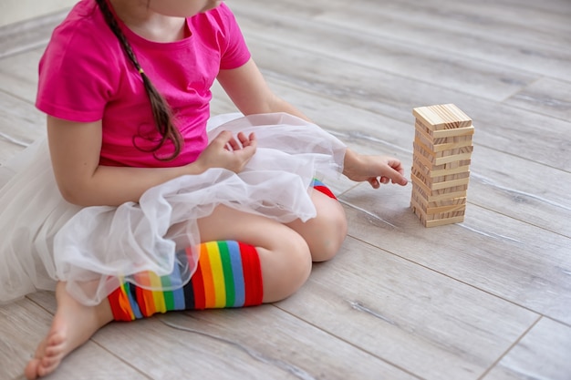 Una niña jugando un juego de maderas en el piso de la habitación.