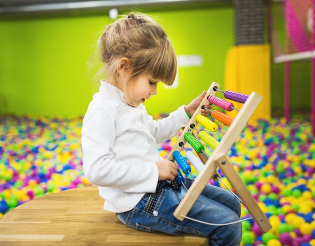 Niña jugando con un juguete de madera de ábaco