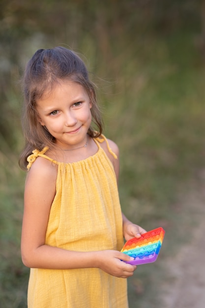 Niña jugando con un juguete pop, en la naturaleza