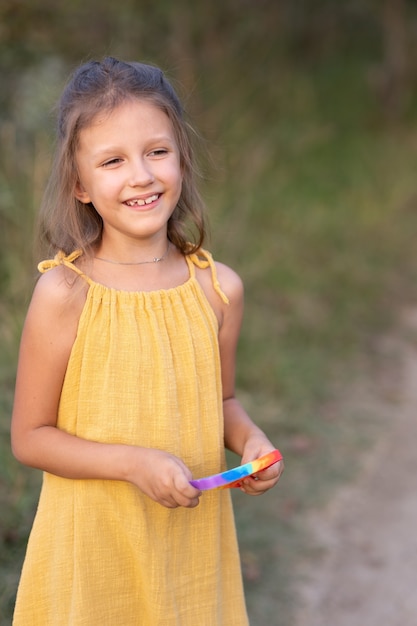 Niña jugando con un juguete pop, en la naturaleza