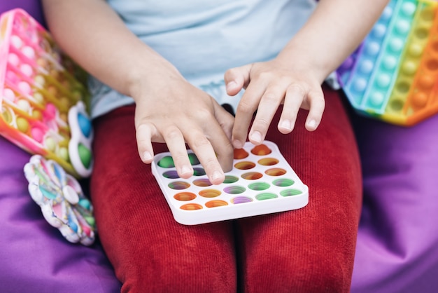 niña jugando con un juguete popit closeup manos de los niños jugar con el arco iris pop it fidget toy