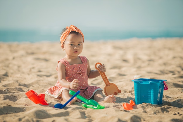 Niña jugando con juguetes de playa en la playa