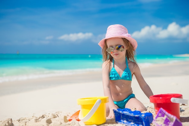 Niña jugando con juguetes de playa durante vacaciones tropicales