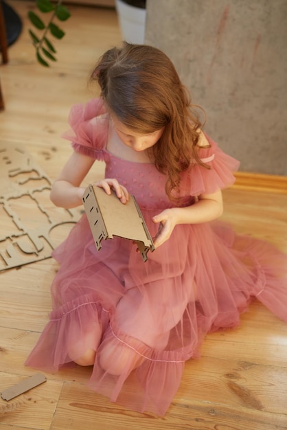 Una niña jugando con muebles de casa de muñecas de juguete de cartón