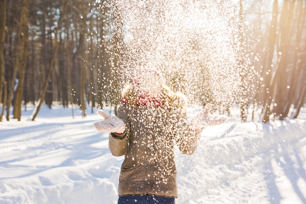Niña jugando con nieve en el parque. Feliz joven divirtiéndose en la nieve.