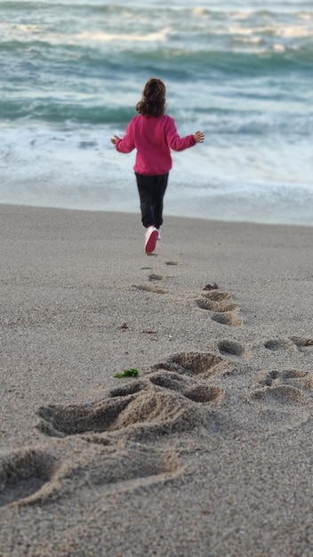 Foto niña jugando con las olas en la playa de riazor en otoño