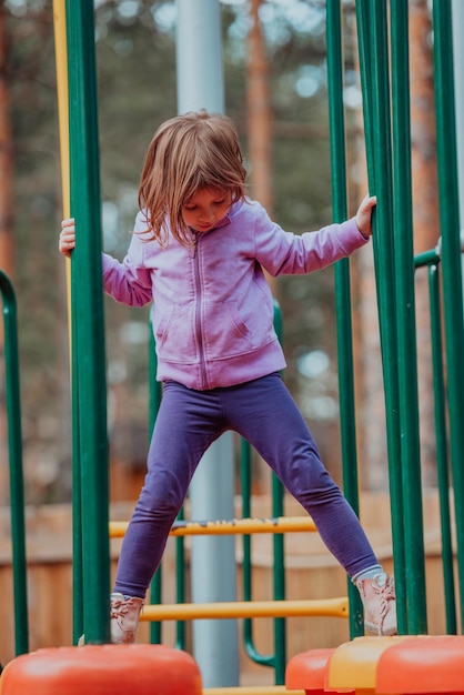 Una niña jugando en el parque. El concepto de socialización familiar en el parque. Una niña se balancea en un columpio, juega juegos creativos.