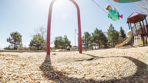 Niña jugando en un parque infantil al aire libre en los suburbios.