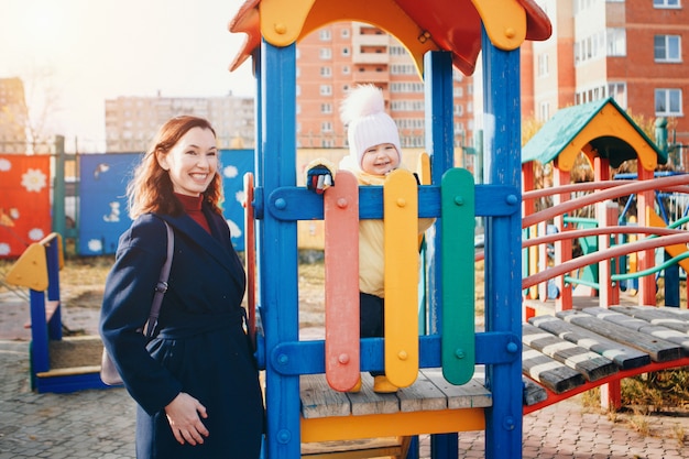 Foto una niña jugando en el patio de la ciudad de los niños. un niño pequeño baja la colina, en el carrusel, sube las cuerdas. concepto de industria del entretenimiento, día familiar, parques infantiles.