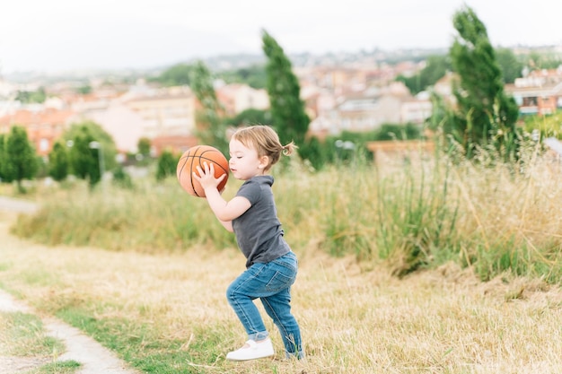 Niña jugando con una pelota en un campo