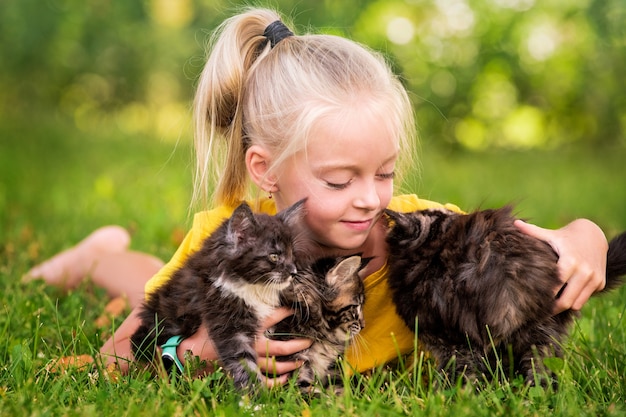 Niña jugando con pequeños gatitos en un cálido y soleado día de verano