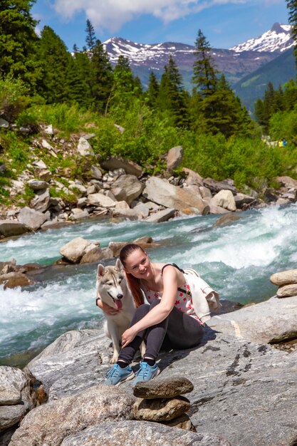 Niña jugando con un perro husky en la orilla de un río de montaña