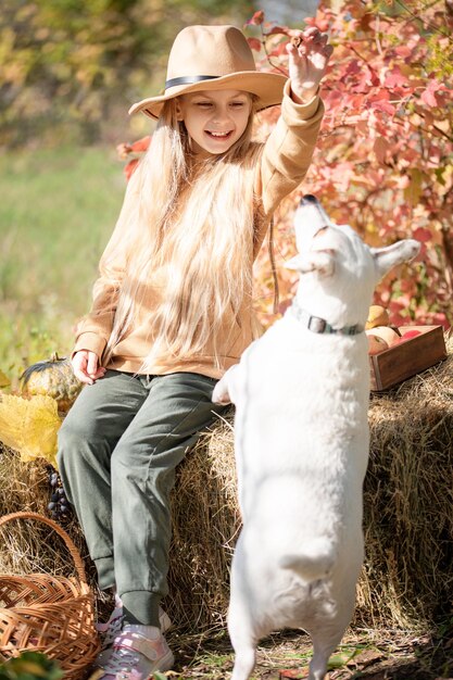 Foto niña jugando con perro en el jardín de otoño