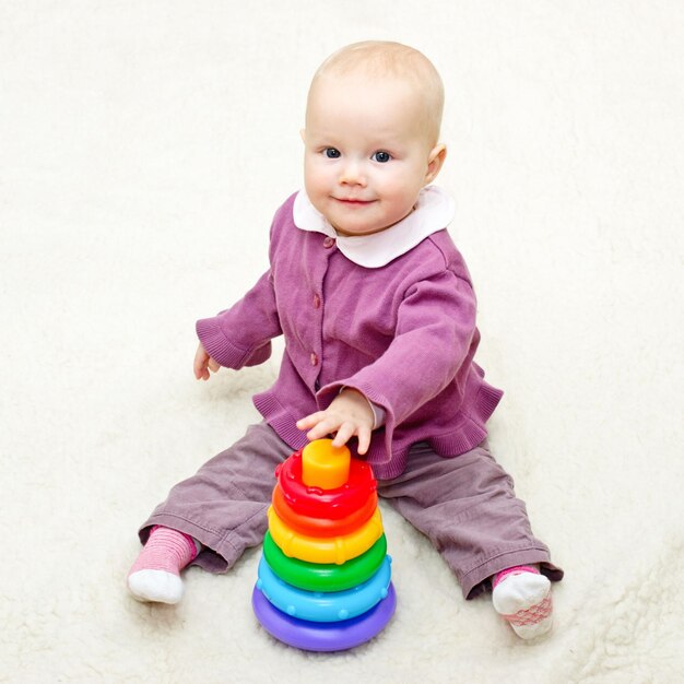 Foto niña jugando con pirámide de colores