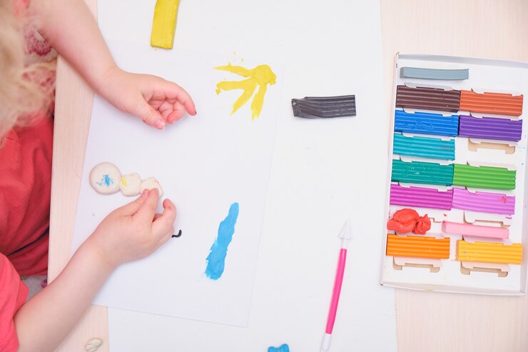Foto niña jugando con plastilina de colores sobre la mesa. juego de educación en casa con arcilla. concepto de desarrollo temprano que el niño esculpe a partir de plastilina