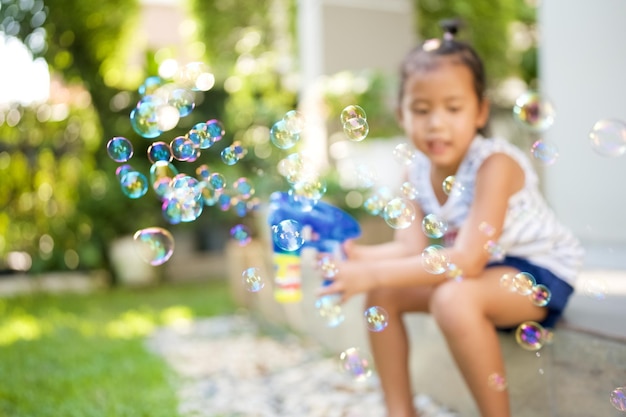 Foto niña jugando pompas de jabón en el jardín