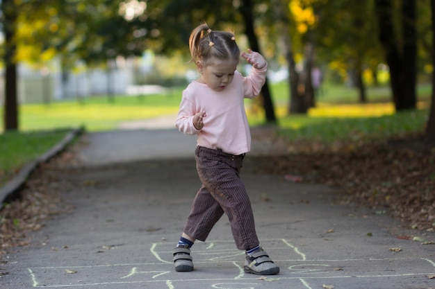 Niña jugando a la rayuela en el parque de verano