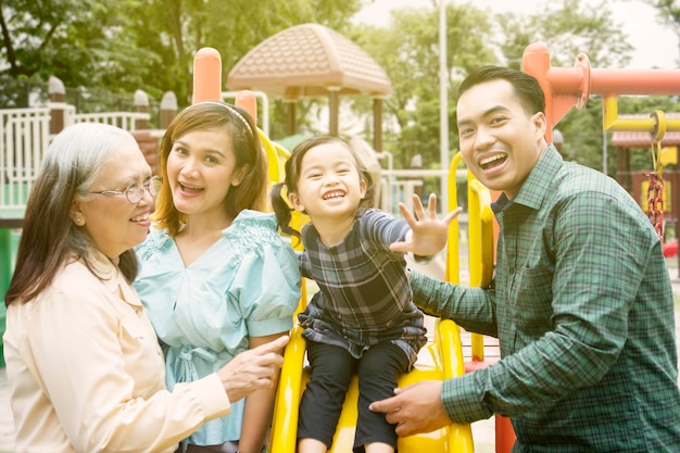 Niña jugando con su familia en el patio de recreo