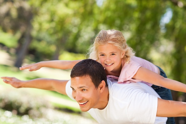 Niña jugando con su padre en el parque