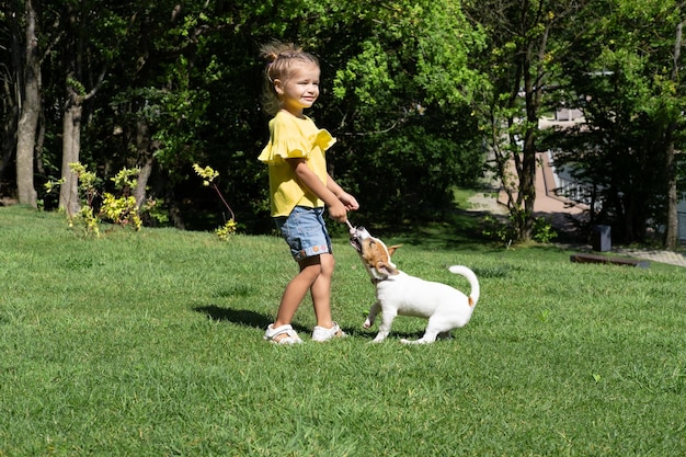 Niña jugando con su perro mascota Jack Russell Terrier en el parque