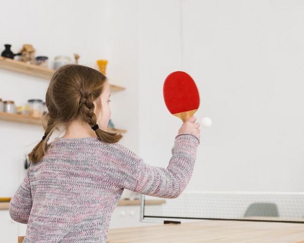 Foto niña jugando tenis de mesa en el interior