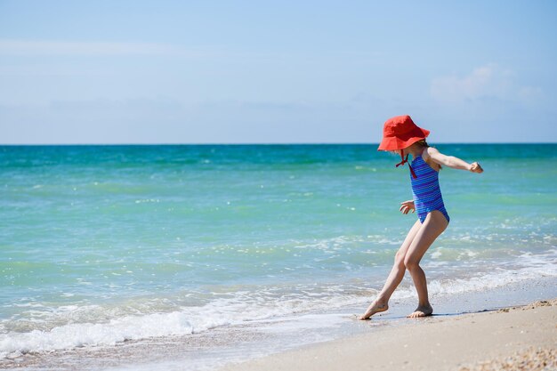 Niña jugar en la playa de arena de mar