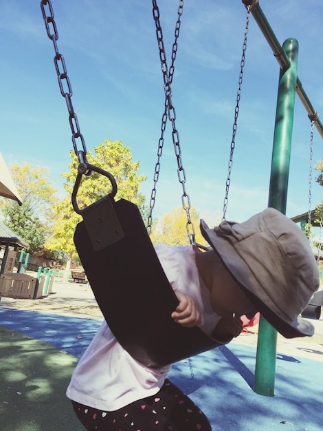 Foto niña juguetona en el columpio en el patio de recreo