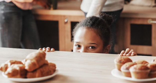 Niña juguetona mirando en secreto los dulces en la cocina