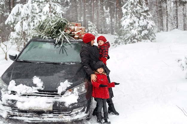 Una niña junto a la madre y un coche con un árbol de Navidad apunta con su mano a un lado en el espacio de la copia