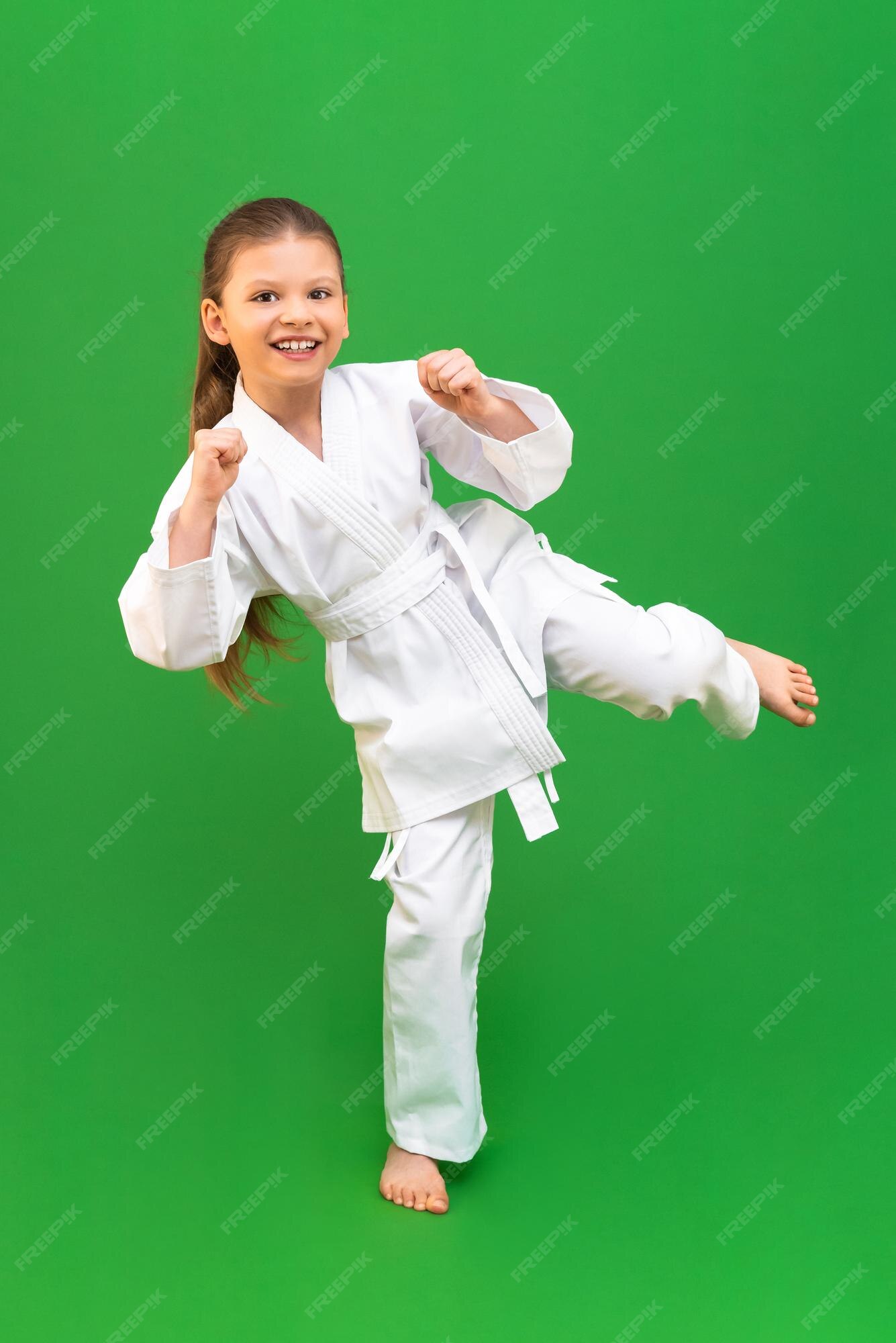 Una niña en un kimono blanco hace una patada artes karate judo thai deportes como niño | Foto Premium