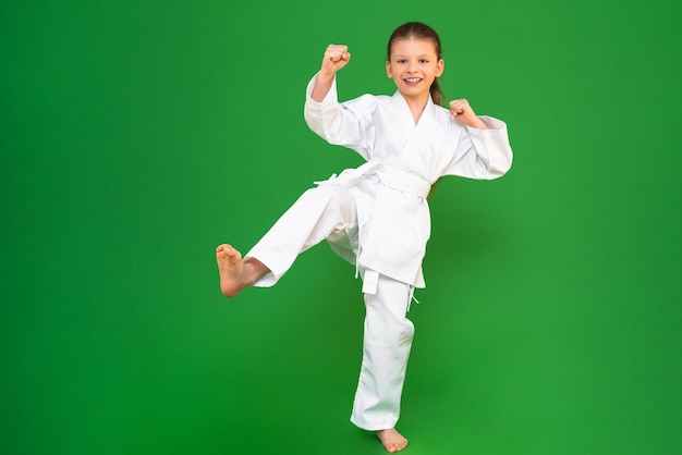 Una niña en un kimono blanco hace una patada artes marciales karate judo Muay Thai deportes como un niño