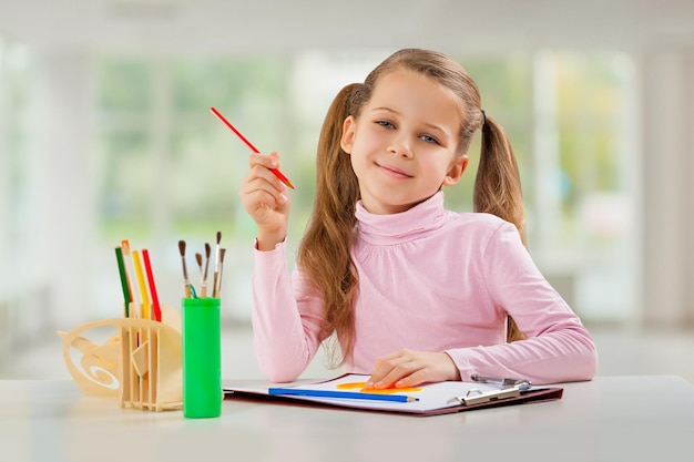 Una niña con lápiz sentado en la mesa