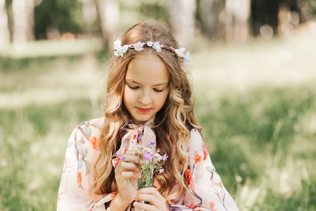 Niña con largo cabello blanco y un ramo de flores silvestres en el parque