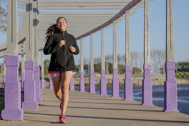 Niña latina corriendo por una pérgola a lo largo de la orilla del río