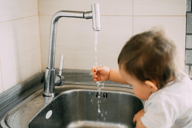 La niña se lava las manos sola en la cocina