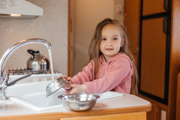 Niña lavando platos en la cocina de un remolque de viaje