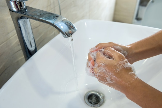 Niña lavándose las manos con jabón en el baño para la higiene personal y la prevención de la propagación de Covid19.
