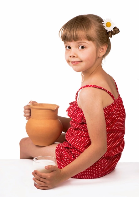 Niña y leche niña linda sosteniendo una jarra de arcilla con leche aislada en el fondo blanco