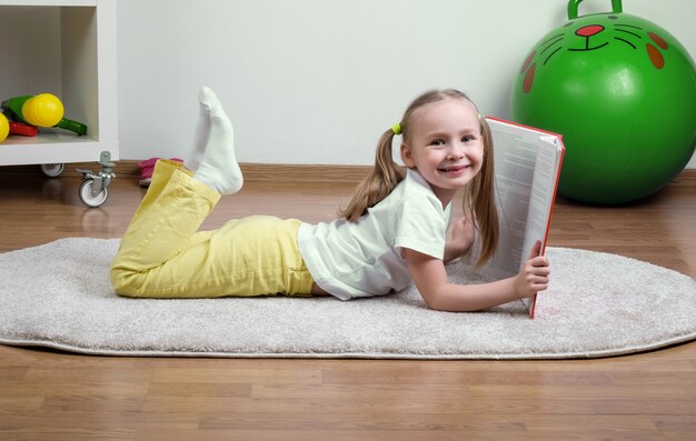 Niña lee un libro en la alfombra