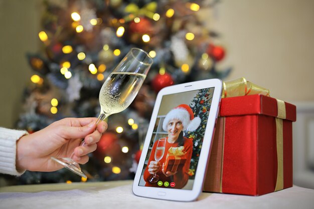 Una niña levanta una copa a su compañero que está hablando con ella por teléfono en la víspera de Navidad