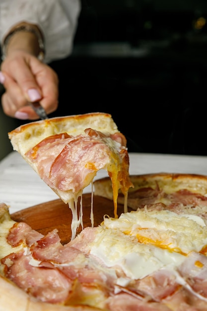 niña levanta pizza sobre la mesa El queso se estira