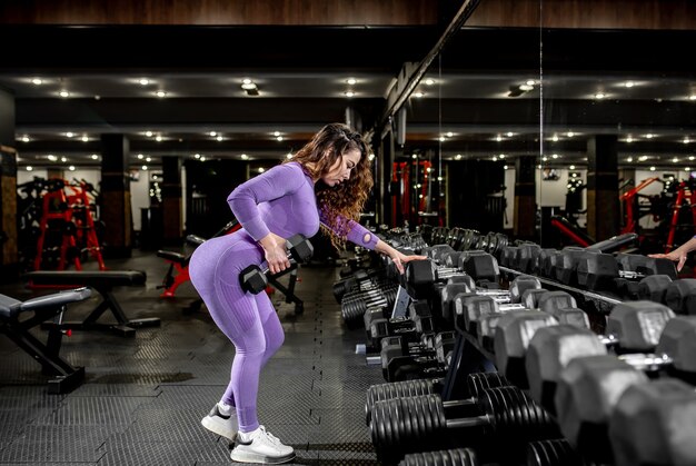 Niña levantando pesas en el gimnasio. concepto de estilo de vida saludable